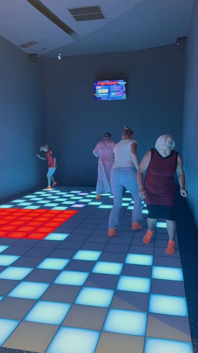 Adulți în mișcare pe podeaua LED luminată roșu și verde la Hai Pixel, Chișinău
