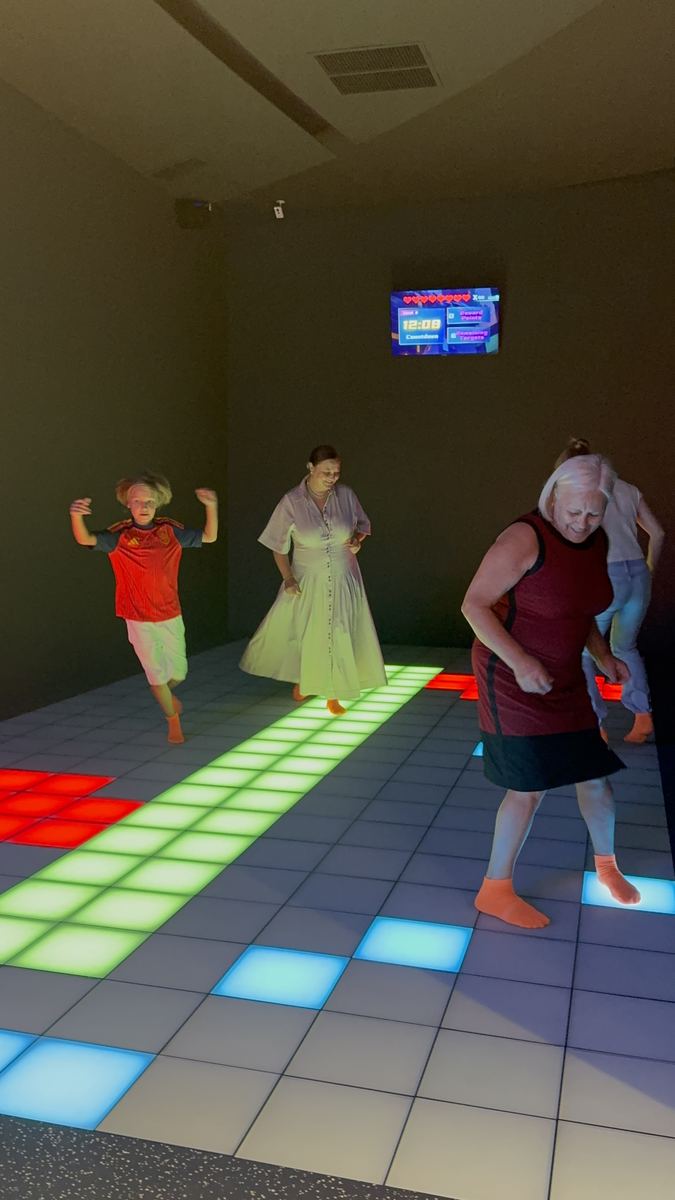 Adult în mișcare pe podeaua LED interactivă de la Hai Pixel, cu șosete antiderapante portocalii
