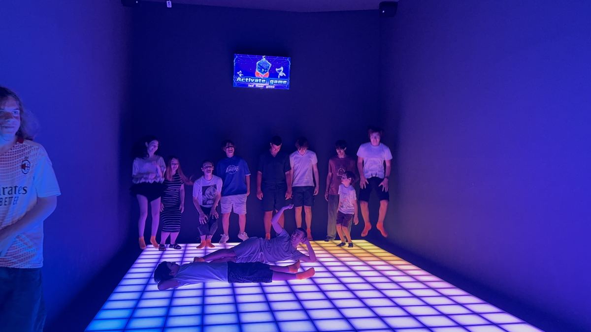 Copii jucând pe echipe pe podeaua LED albastră și violet la Hai Pixel în Chișinău