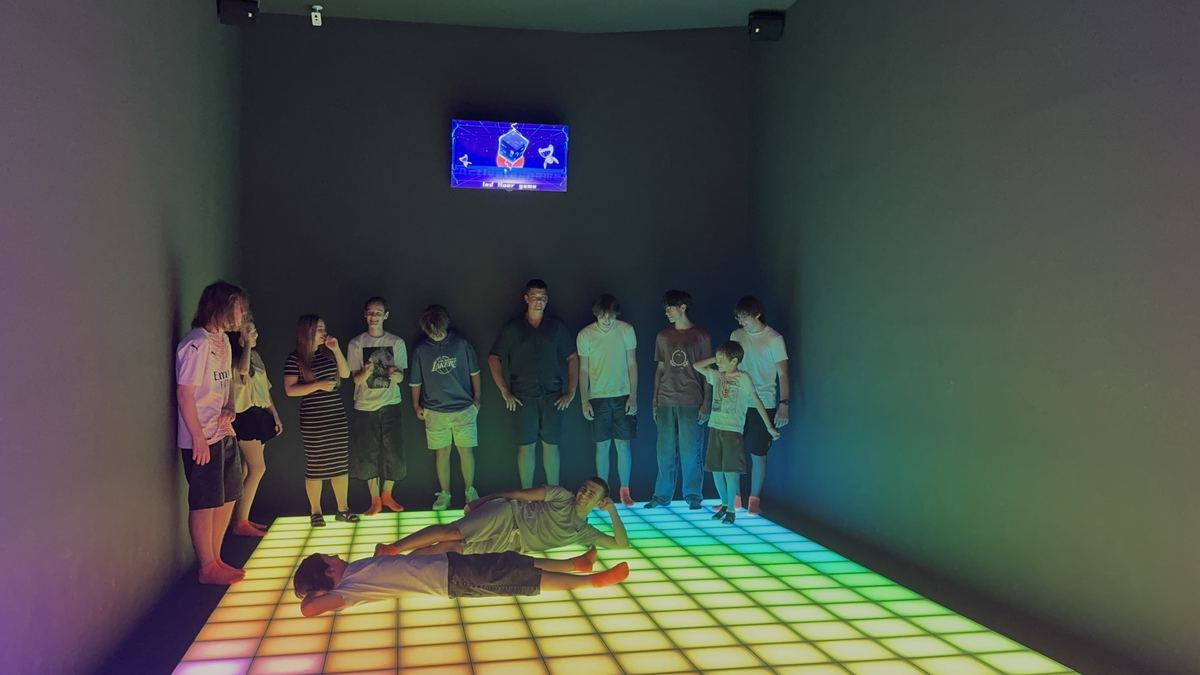 Copii aliniați pe podeaua LED interactivă de la Hai Pixel din Chișinău, cu monitorul de scor aprins pe perete