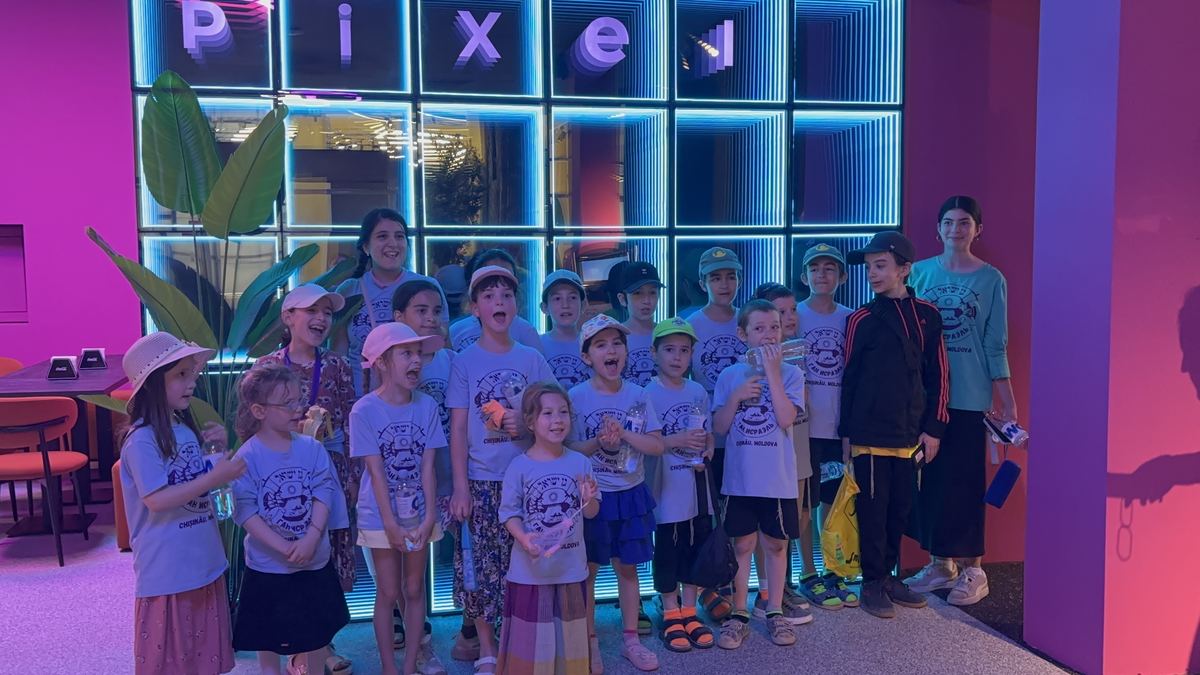 Grup mare în tricouri identice, aliniat lângă peretele cu litere neon Pixel de la Hai Pixel, Chișinău