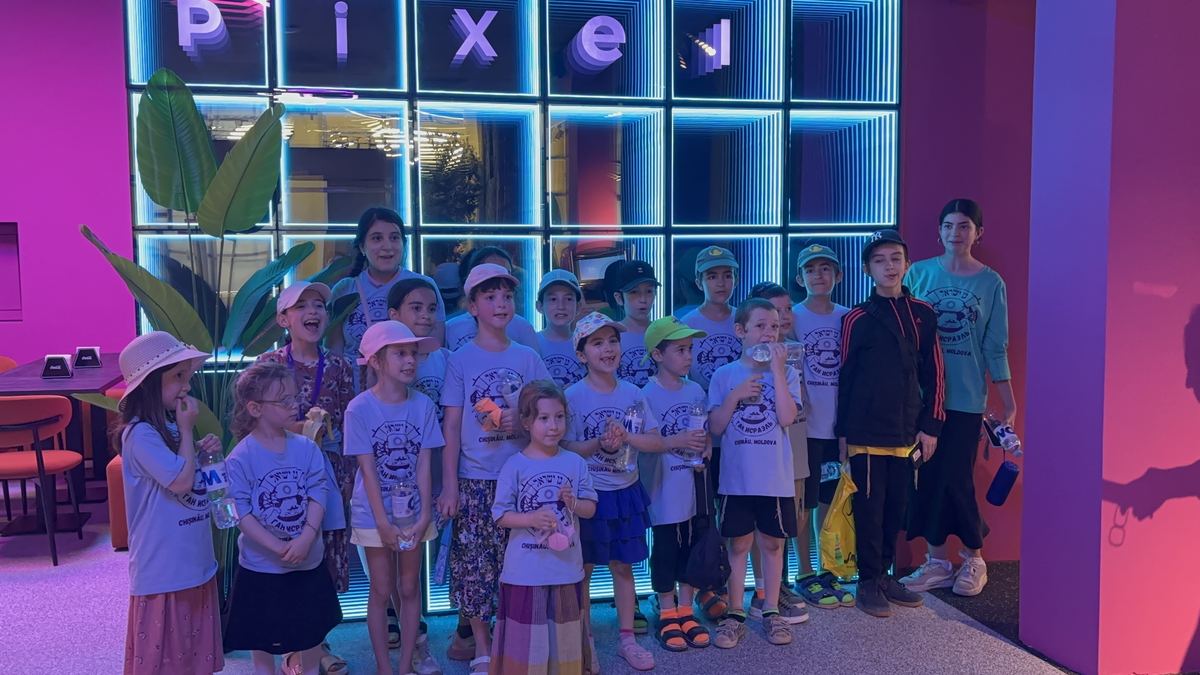 Grup mare de copii de școală cu adulții însoțitori, fotografiați lângă peretele neon Pixel de la Hai Pixel, Chișinău