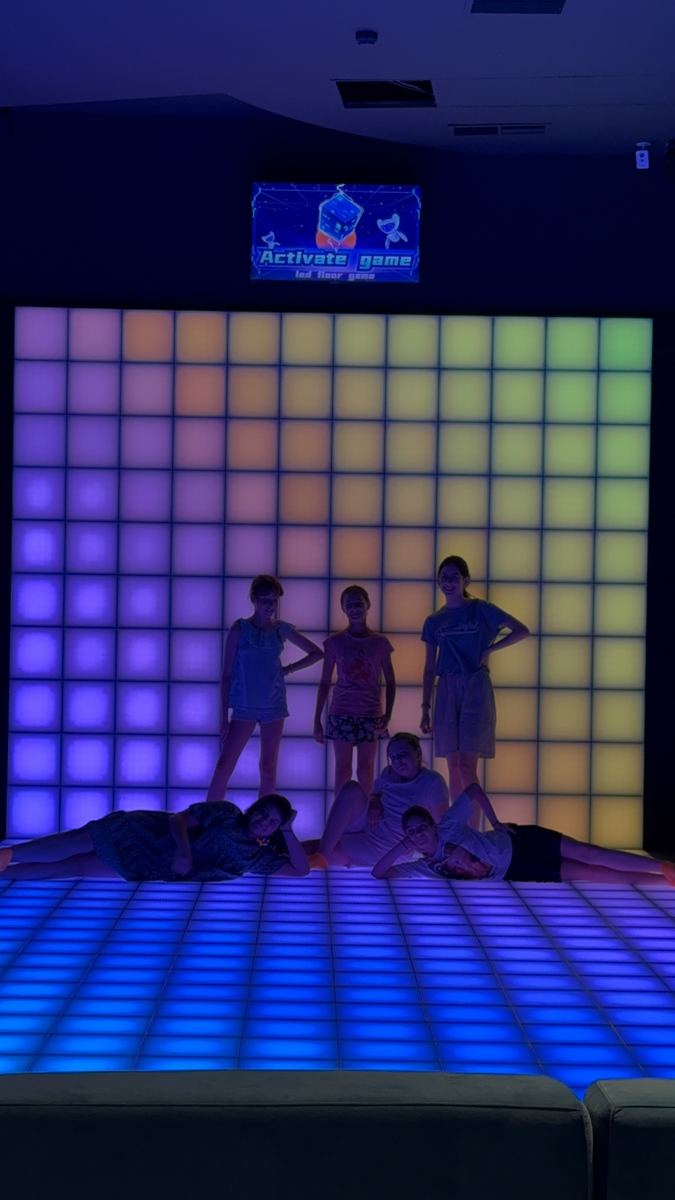 Peretele LED interactiv luminat în roz și mov, cu jucători în fața lui, la Hai Pixel din Chișinău