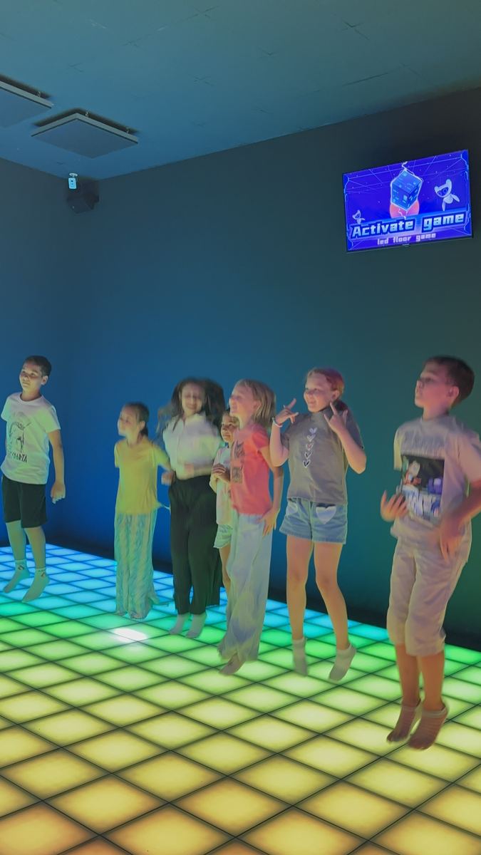 Prieteni jucând împreună pe podeaua LED galbenă la Hai Pixel, Chișinău