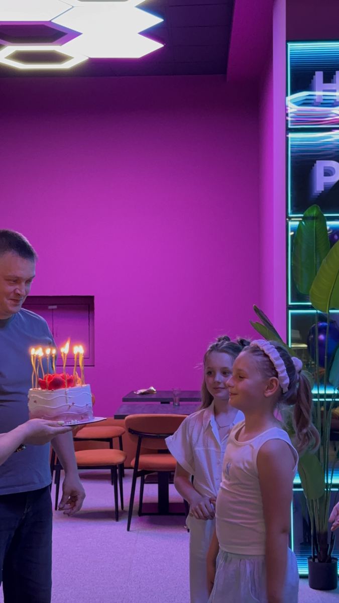 Tortul aniversar adus copilului sărbătorit în zona de celebrare de la Hai Pixel, cu peretele neon în spate
